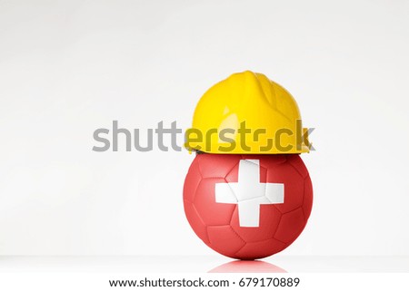still life image of football wearing a hard hat with the Switzerland flag  superimposed on the football