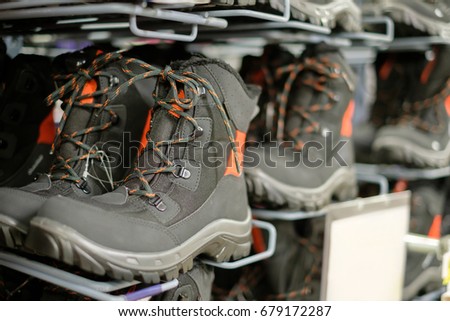Row of black winter boots for outdoor activities on stands in sport store