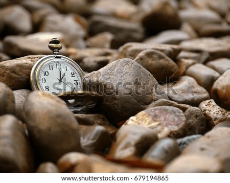 A retro clock is placed on stones in a natural park