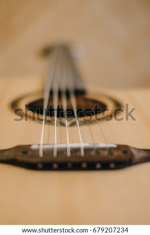 A brown acoustic guitar on blur focus.