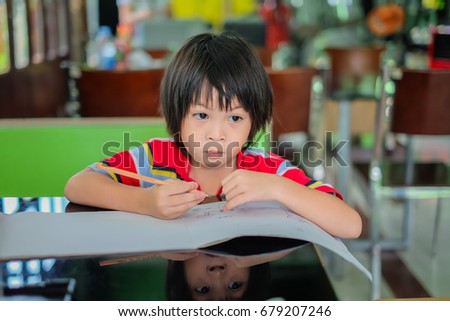 the cute boy drawing a picture. a smart kid writing letter on the book.