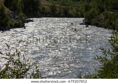 Bright Animas River in Durango, Colorado with the silhouette of three kayakers