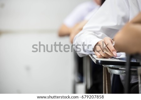 soft focus.university or high school student holding pencil.sitting on row chair writing final exam in examination room or study in classroom.student in uniform.education concept Royalty-Free Stock Photo #679207858
