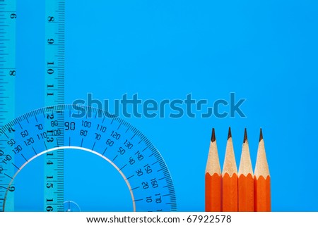 Transparent plastic protractor and ruler near pencils on blue background with copy space