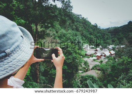 Woman taking photos with smartphone at hill.