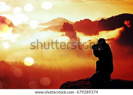Film grain effect. Professional photographer silhouette above a clouds sea, misty mountains
