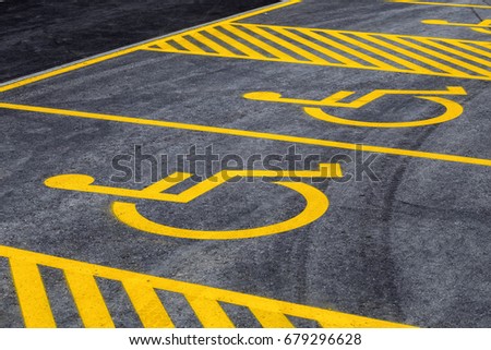 Parking lot with painted yellow sign of wheelchair on asphalt, parking spaces for disabled visitors. Disabled parking spaces.