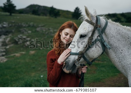 Young beautiful woman walks on nature with her horse.