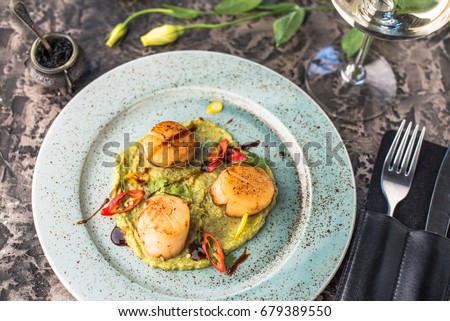 Seafood snack -  Sea scallops and vegetables, glass of wine and flowers. Close-up on a black table. Healthy fresh food. Royalty-Free Stock Photo #679389550