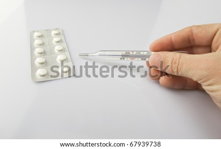Man's hand with thermometer on white background with  pills