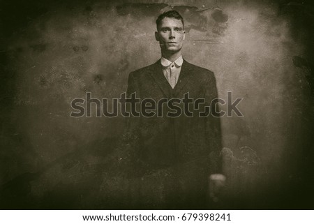 Antique wet plate photo of 1920s english gangster in suit standing with cigarette.