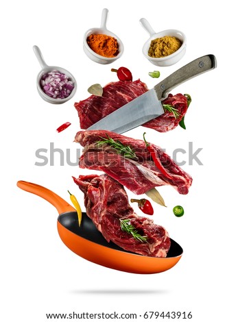 Flying raw steaks, with ingredients for cooking, from pan. wooden bowls with spices. Concept of food preparation. Isolated on white background. Extra high resolution
