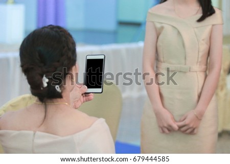 Woman taking a photo of young girl with mobile smart phone