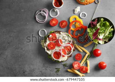 Composition with tasty burger and vegetables on table