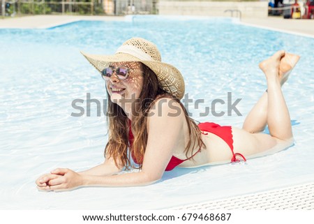 Young beautiful woman with hat relaxes in the hydromassage of swimming pool. Concept of young people having fun in summertime