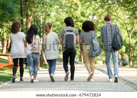 Back view picture of multiethnic group of young students walking outdoors.