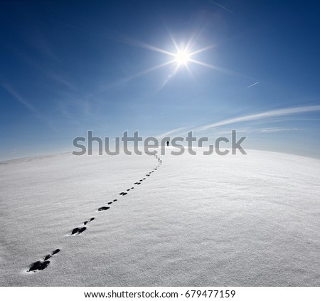 Man,Earth,Universe. Lonely Man Walking On Snow Crust Field On The Trail Of  Hare At The Background Of The Sun And Flying Plane. Abstract Photo Silhouette Of A Man On The Road In Winter Empty Field