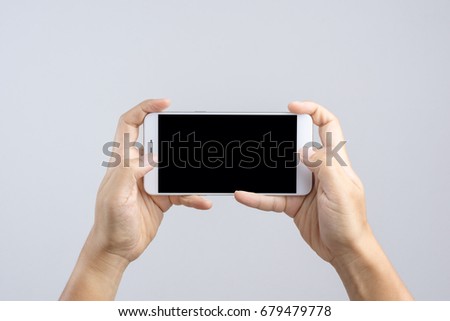 Hand holding new 6 inch smart phone with blank screen and  playing game gesture finger on white background Royalty-Free Stock Photo #679479778