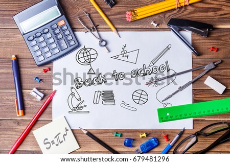 Album sheet with text - back to school and student material on wooden table. Top view