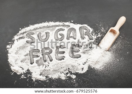 Sugar free written with sugar together wooden spoon on black background.