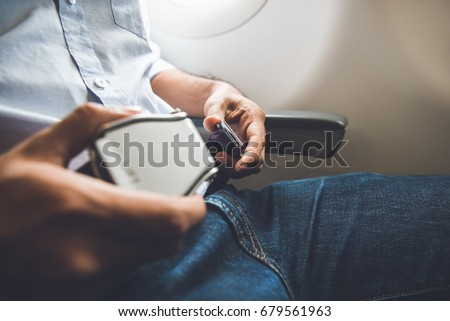 Male passenger fastening seat belt while sitting on the airplane for safe flight Royalty-Free Stock Photo #679561963