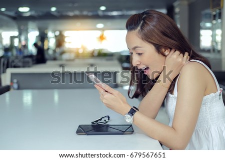 Charming woman with beautiful smile reading good news on mobile phone during rest in coffee shop, happy Caucasian female watching her photos on cell telephone while relaxing in cafe during free time