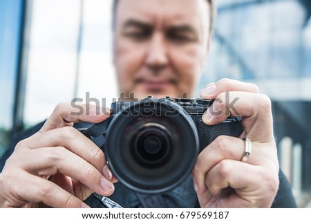 Photographer with  modern  camera when photographing. close up image against glasses business building. closeup of professional dsl camera with fixed lens. no face. unrecognizable person