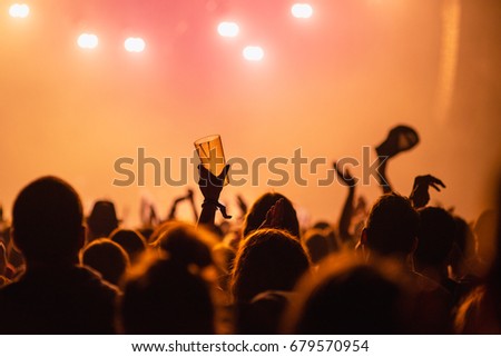Hands in the air on party concert on summer festival - someone holding glass of beer in the air Royalty-Free Stock Photo #679570954