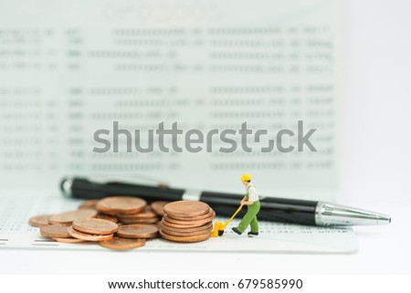 Miniature people rolling coin on the stack of coins and man putting coin on the tallest stack,money saving, finance concept.