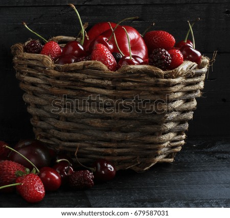 Red fruits in liana basket with black wood background.