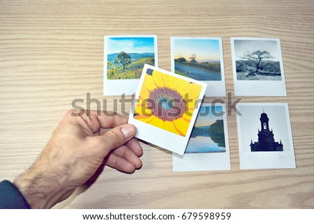 Man's hand picking one photo among six options over a wood tabletop