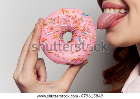 Woman eating a donut close-up on a gray background                               