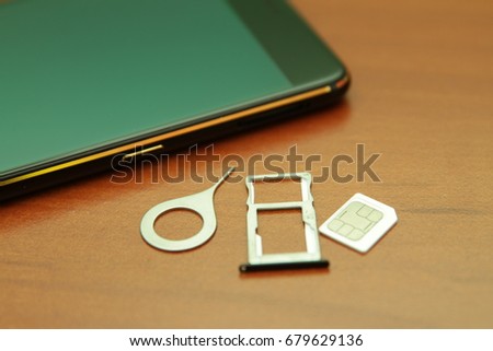 Black smartphone lying on a wooden table.