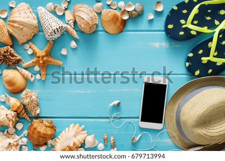 Vacation background on blue wood, top view. Beach accessories, flip flops, smartphone and seashells