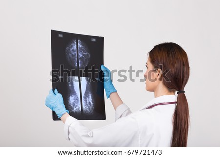 Thoughtful female doctor looking at the Mammogram film image.