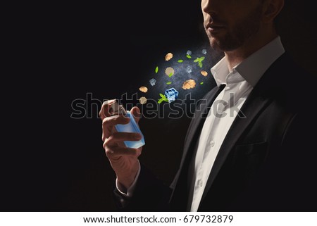 Handsome young man spraying perfume with different components onto body on black background