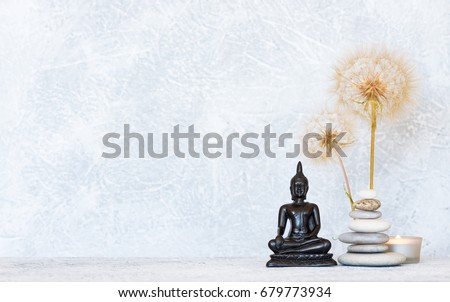 Buddha, pyramid of pebbles, burning candle and dandelion flowers as zen background