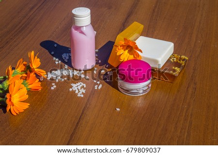 Beauty treatment products and calendula flowers on wooden background. Spa set