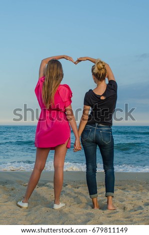 Two girls hold hands and create a heart, lesbian love