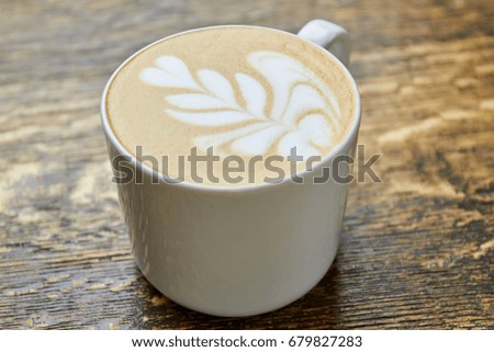 Latte cup on wood. Flower coffee foam art.