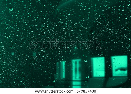 Abstract background. Wet window with drops of water. Night rainy cityscape with blur effect.