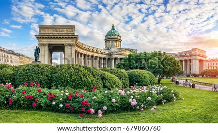 Kazan Cathedral in St. Petersburg under a blue sky with clouds and beautiful red and white peonies in front of him Royalty-Free Stock Photo #679860760