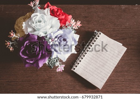 Note book with flower vase on wooden background