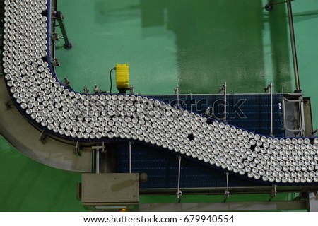 Conveyor line carrying thousands aluminum beverage cans at factory from top view Royalty-Free Stock Photo #679940554
