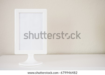 Empty white picture photo frame with light beige paint background
