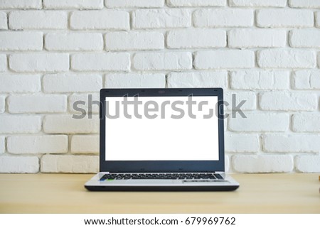 Laptop computer on wood desk with white brick wall background