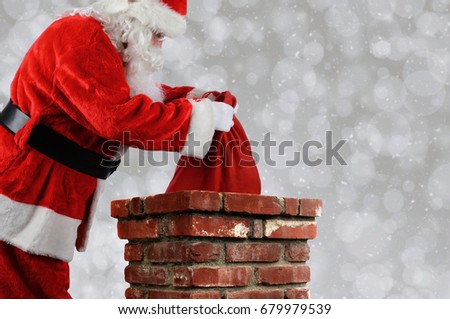 Closeup of Santa Claus placing his bag inside a chimney. Horizontal with copy space over a light bokeh background.