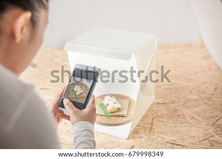 Young women taking photo to roll cake with cell telephone or smartphone digital camera for Post to show and sell Online on the Internet . for selling online business internet of things concept