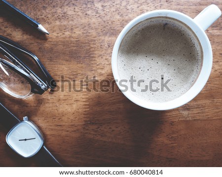 This is office equipment and hot coffee in minimal style, The picture of pencil, glasses, watch and hot coffee on wooden table. soft tone color,  minimal style