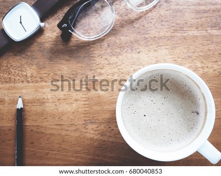 This is office equipment and hot coffee in minimal style, The picture of pencil, glasses, watch and hot coffee on wooden table. soft tone color,  minimal style